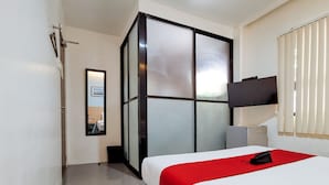 A hotel room with a bed, a TV mounted on the wall, and a sliding glass door. - RedDoorz near Trade School Gensan (General Santos)