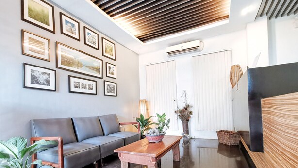 A modern living room with a grey sofa, a wooden coffee table, and framed pictures on the wall. - RedDoorz near Trade School Gensan (General Santos)