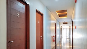 A hotel corridor with wooden doors, a fire extinguisher, and a ceiling vent. - RedDoorz near Trade School Gensan (General Santos)