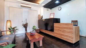 A reception area with a wooden reception desk, a clock on the wall, and a small table with decorative items. - RedDoorz near Trade School Gensan (General Santos)