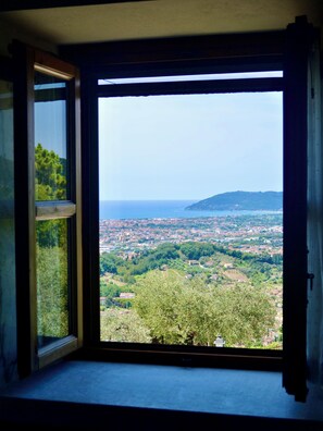 Ein Zimmer mit großem Fenster und Blick auf eine Küstenstadt.