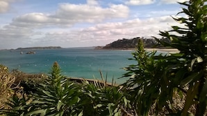 Küstensicht mit blauem Himmel, ruhiger See und weiter Küste im Hintergrund.