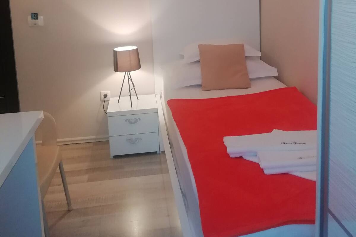 Un dormitorio con cama, mesita de noche, lámpara y candelabro.