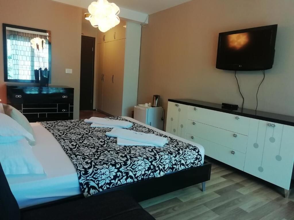 Un dormitorio con una cama, televisor en la pared, cómoda y ventana con vista.