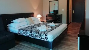 Une chambre d’hôtel moderne équipée d’un grand lit, d’un bureau, d’un miroir et d’une porte.
