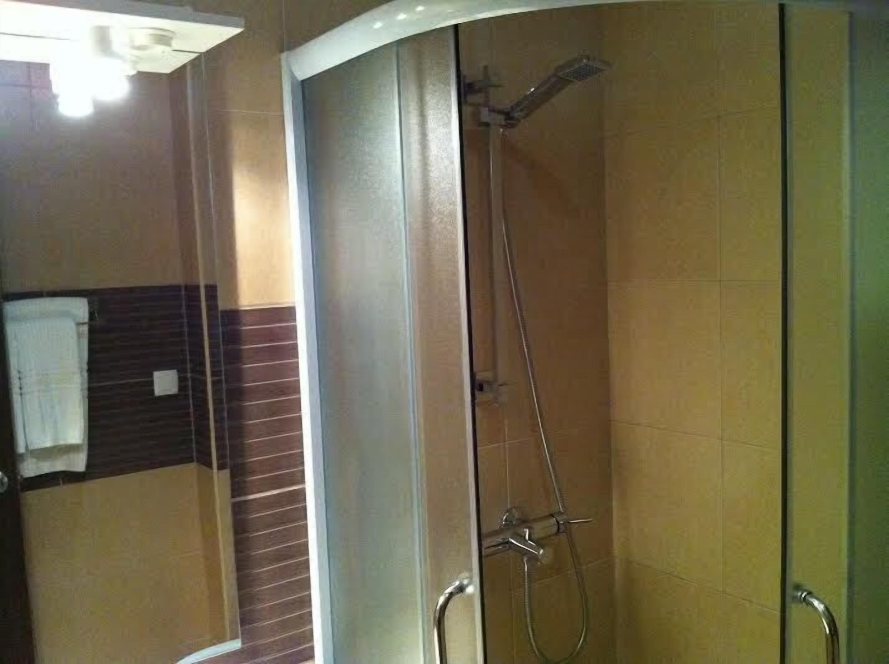 A shower area with a glass door, a towel rack, and a showerhead.