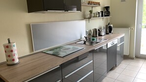 A modern kitchen with a wooden countertop, stainless steel appliances, and a built-in dishwasher. - New! Stylish city apartment *Netflix,parking lot,close to BHF* (CB)