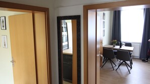 A room with a wooden door, a mirror, a dining table with chairs, and a window with curtains. - New! Stylish city apartment *Netflix,parking lot,close to BHF* (CB)