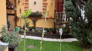 A courtyard with a stone wall, a wooden bench, a planter with flowers, and a small tree. - New! Stylish city apartment *Netflix,parking lot,close to BHF* (CB)