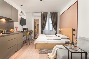 Una habitación de hotel moderna con cama, mesita de noche y una pequeña cocina.