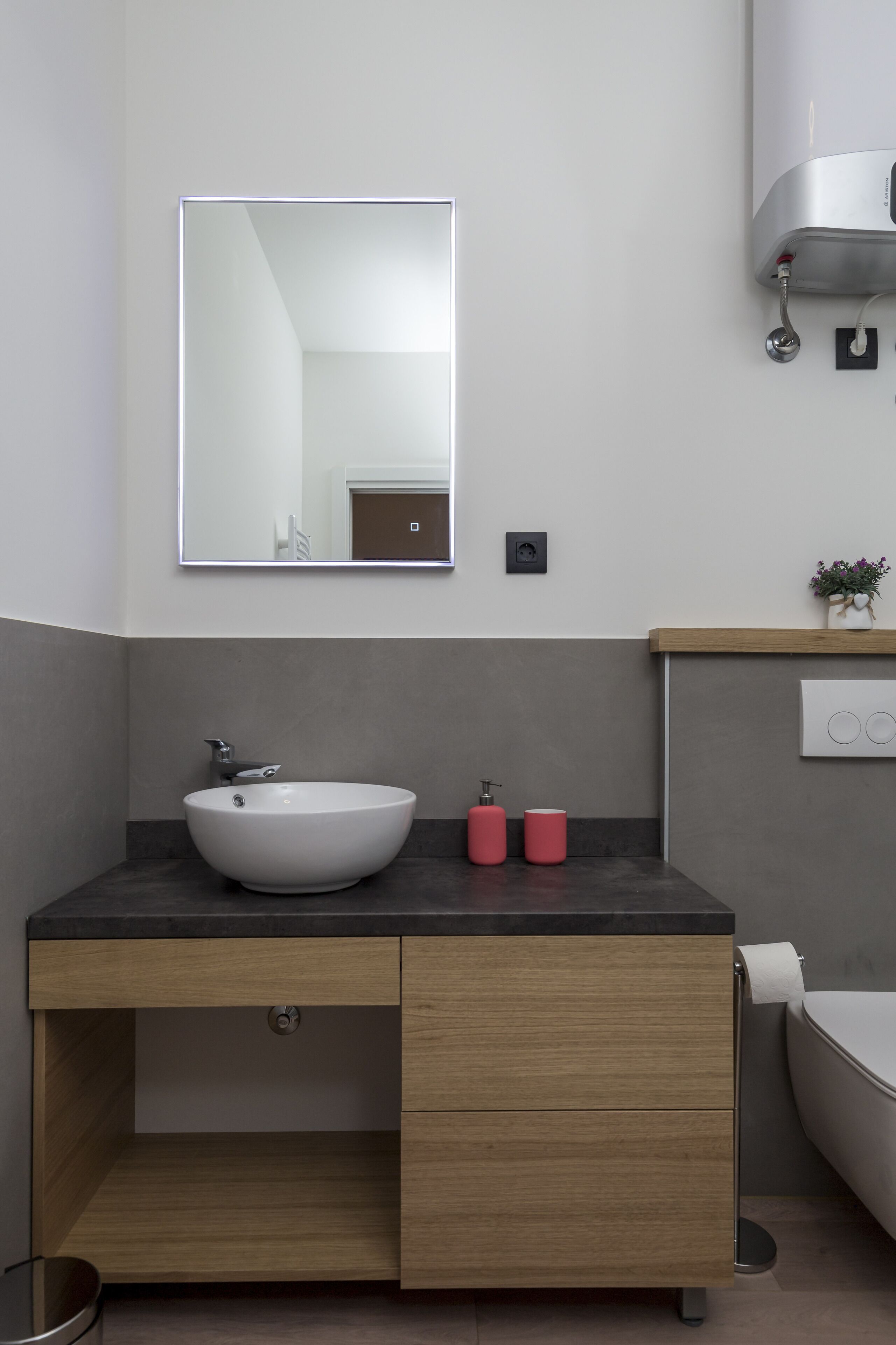Une salle de bain moderne avec un lavabo blanc, un meuble-lavabo en bois et un grand miroir.