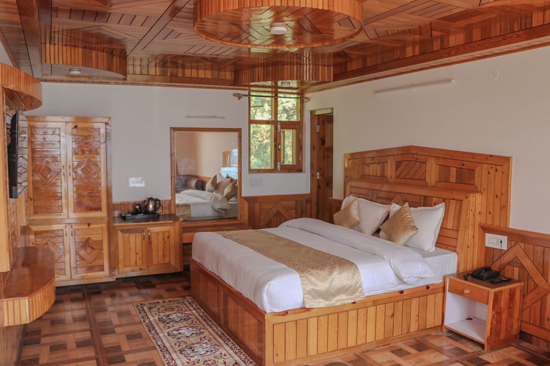 A wooden-themed bedroom with a large bed, a bedside table, a wardrobe, and a mirror.