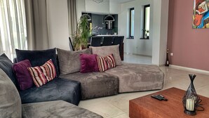 A modern living room with a sectional sofa, a coffee table, and a dining area in the background. - Villa Flora Apartment (Kastav)