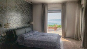 A bedroom with a bed, a window with curtains, and a view of the sea. - Villa Flora Apartment (Kastav)