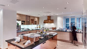 A modern kitchen with wooden cabinets, a central island with breakfast items, and a large window.