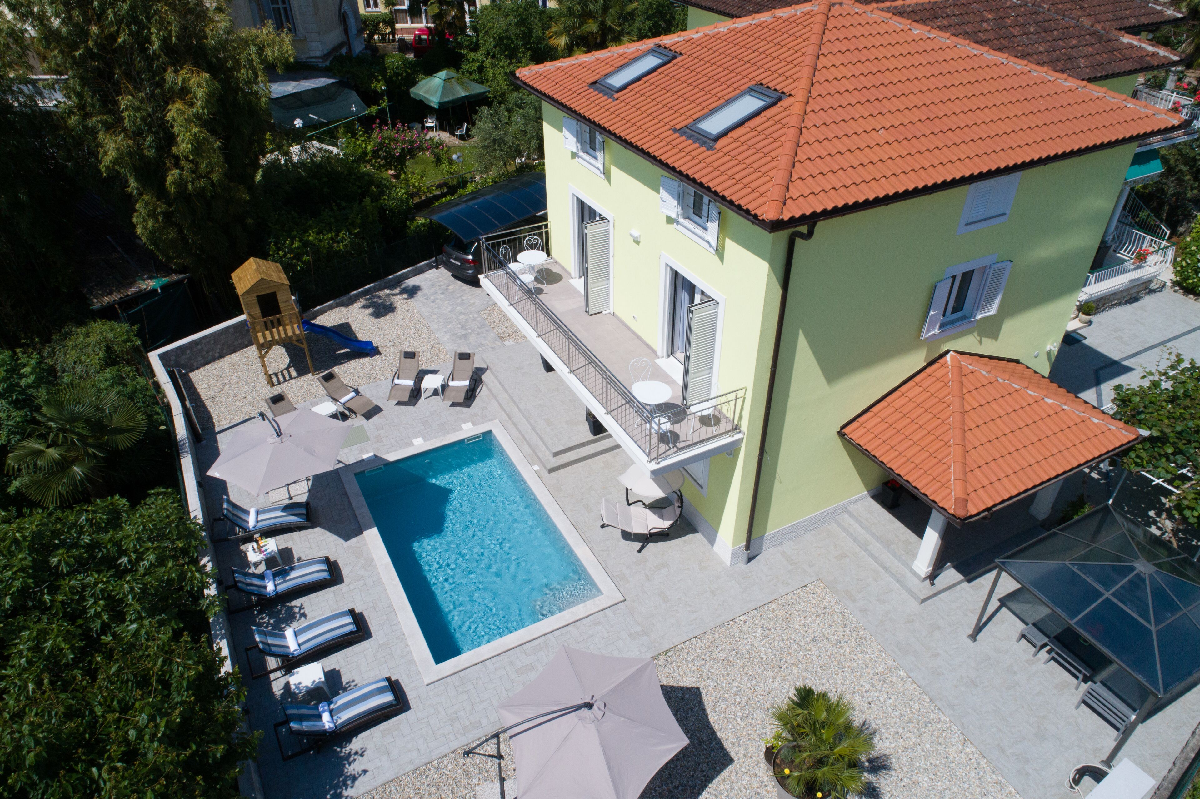 A two-story building with a swimming pool, outdoor seating, and a small play structure.