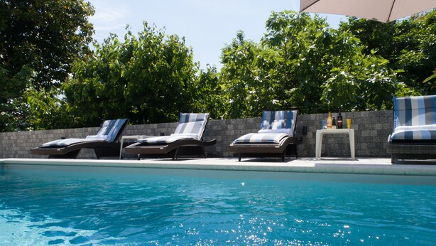 Una piscina con sillones de descanso y una pared de piedra.