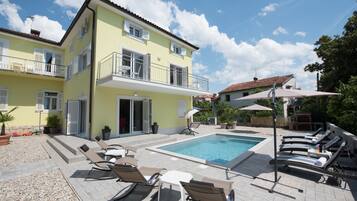 A two-story building with a swimming pool, outdoor seating, and a balcony.