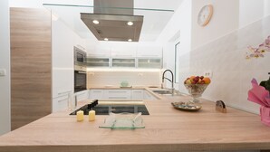 Una cocina moderna con una isla de vidrio, electrodomésticos de acero inoxidable y un frutero sobre la encimera.
