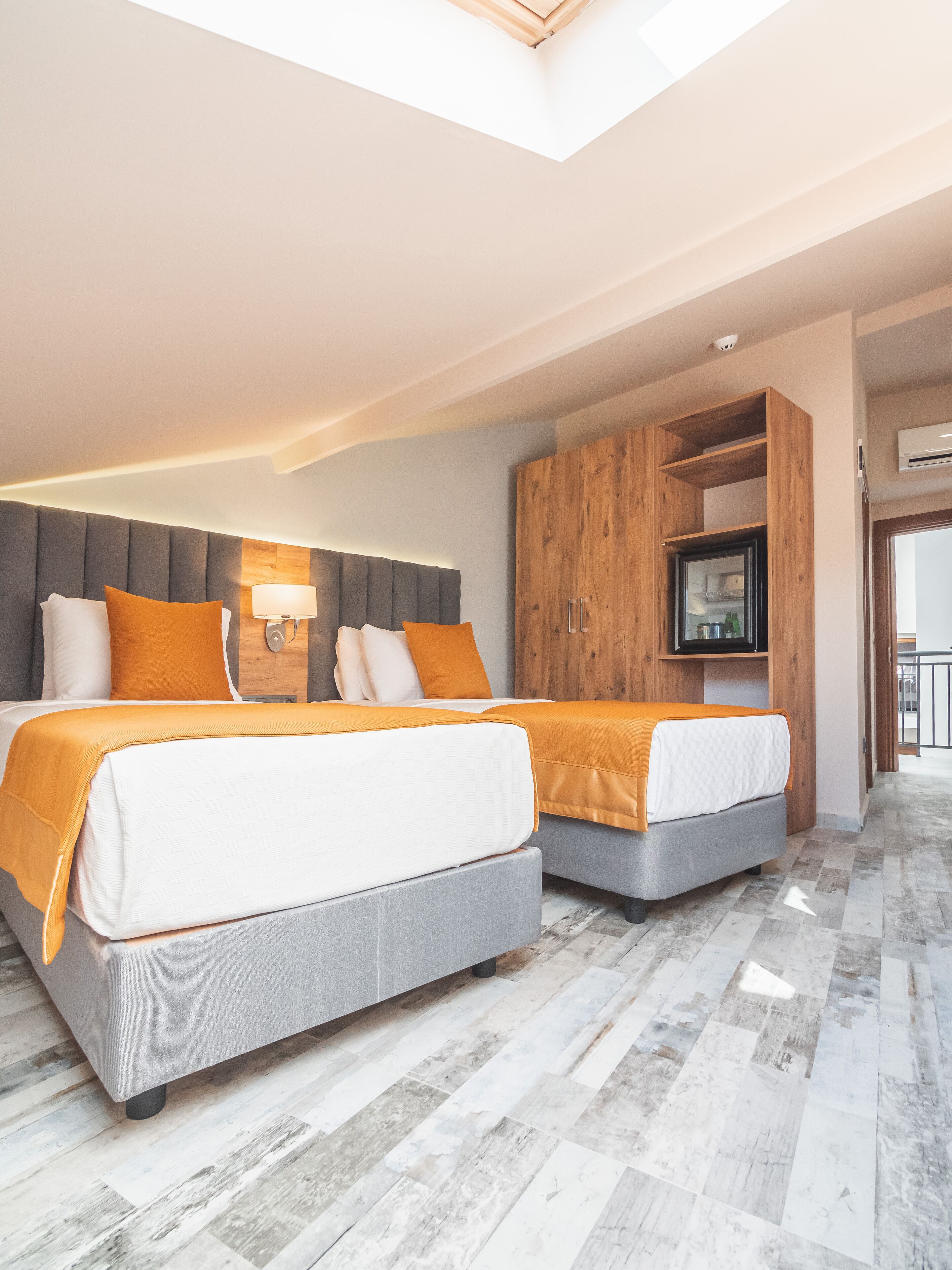Een moderne slaapkamer met twee bedden, een houten garderobe en een televisie.