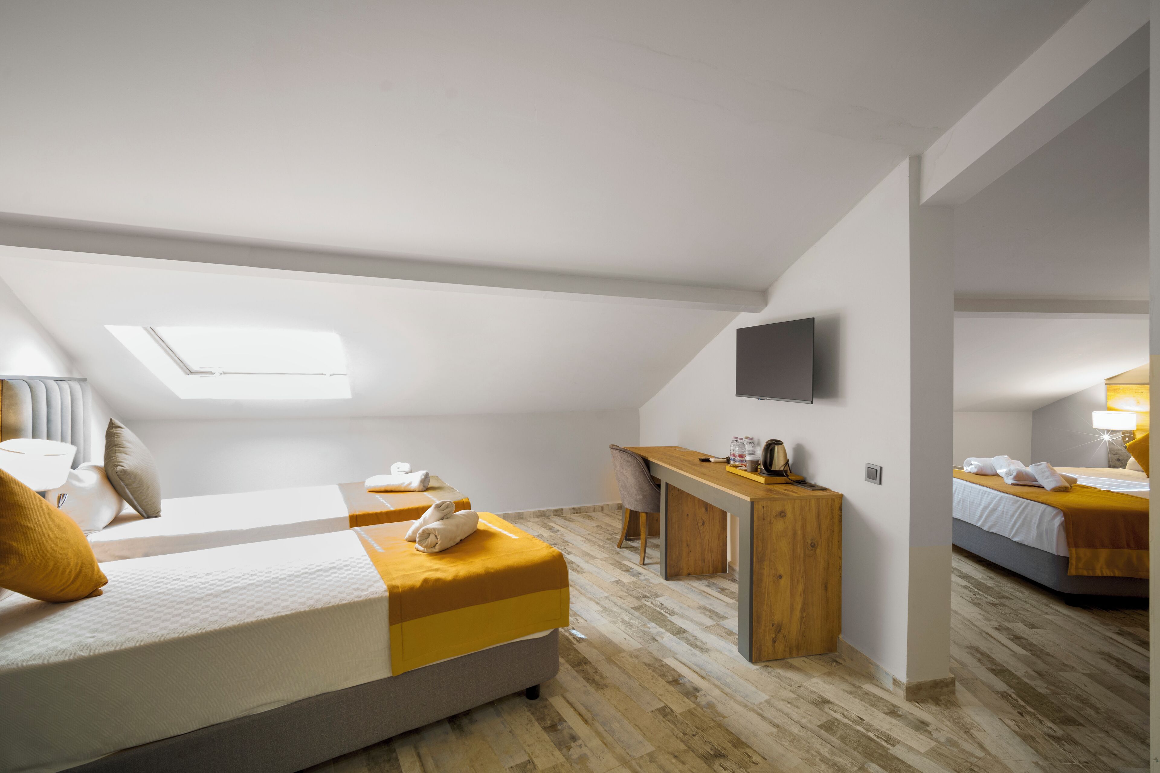 A modern hotel room with a loft bed, a desk, and a TV.