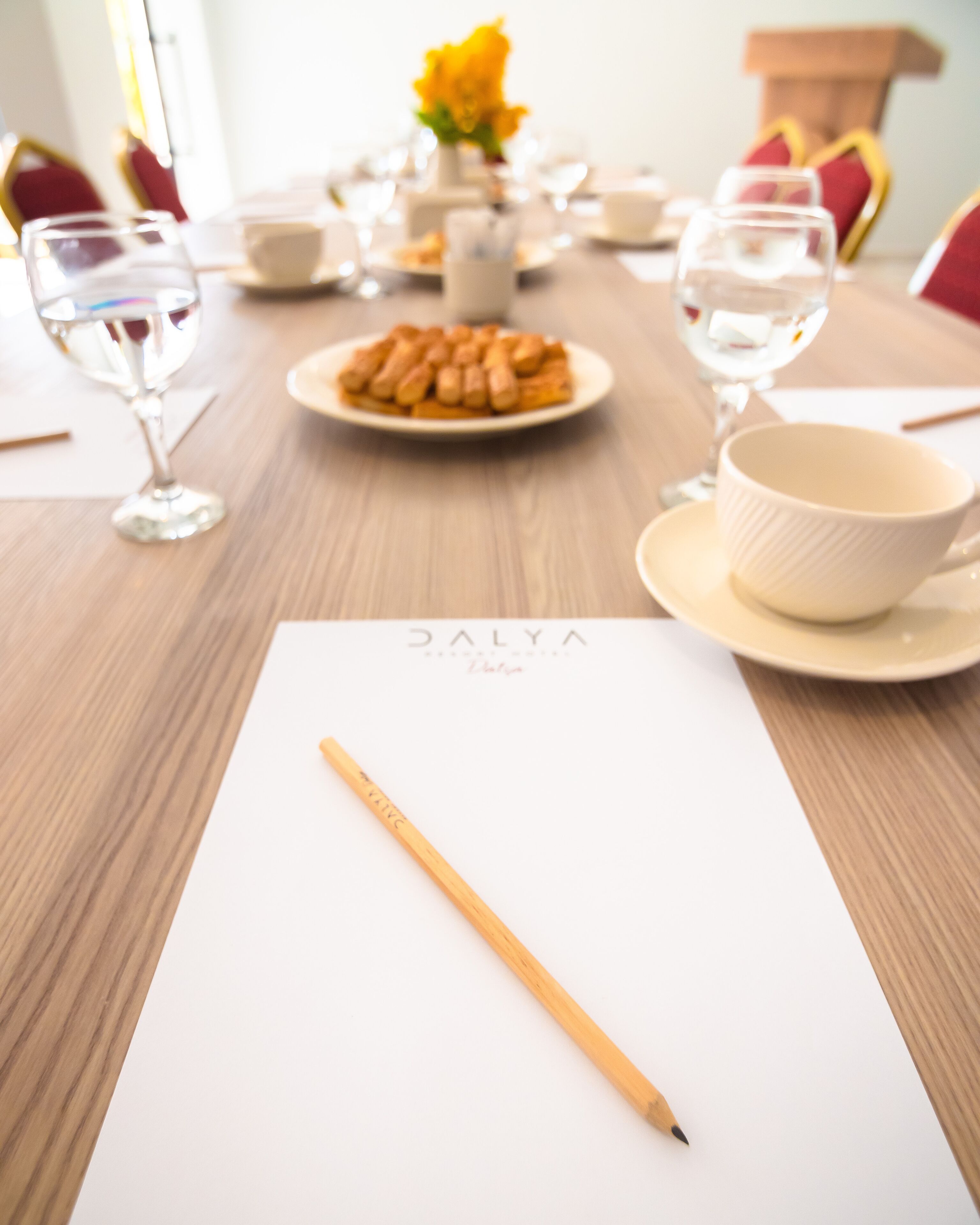 A table with a white placemat, a wooden pencil, a plate of food, and a bowl.