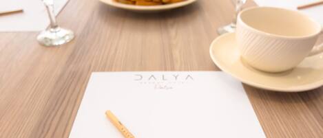 A table with a white placemat, a wooden pencil, a plate of food, and a bowl.