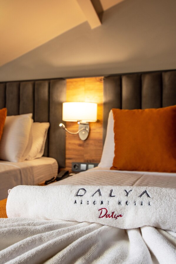A hotel room with a bed, a nightstand, a lamp, and a wall-mounted light fixture.