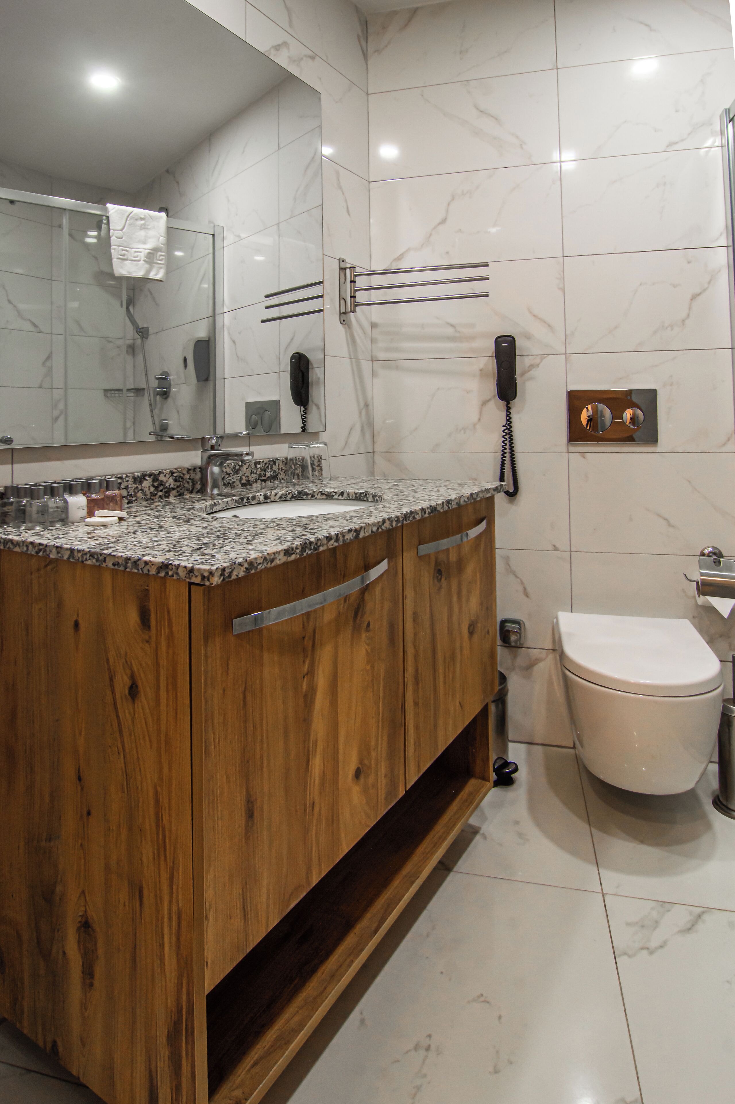 Un bagno con un mobile lavabo in legno, un lavandino, uno specchio, un WC e una zona doccia.