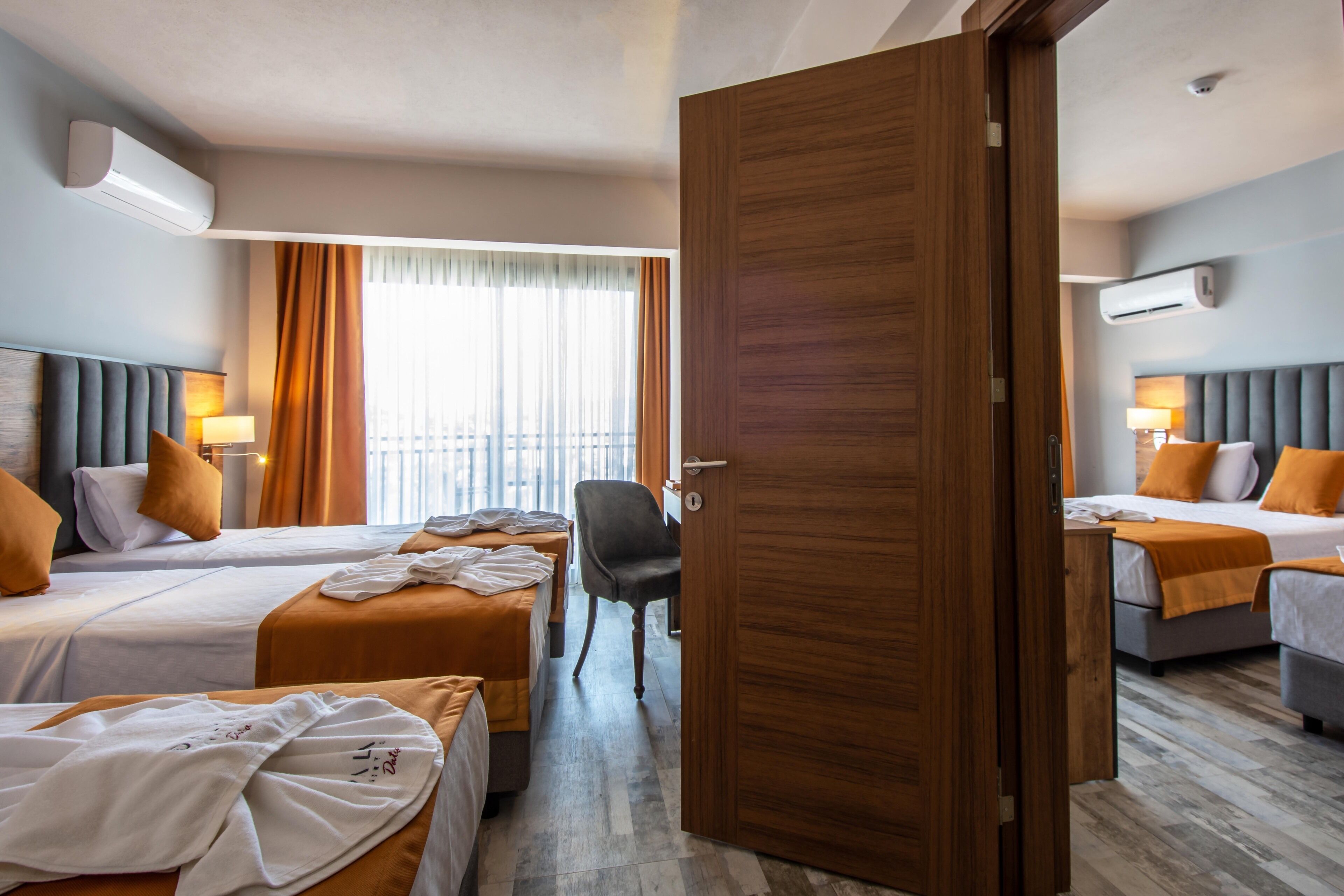 Habitación de hotel con dos camas, una puerta de madera y un equipo de aire acondicionado en la pared.