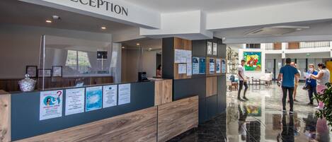 A reception area with a wooden reception desk, a 'RECEPTION' sign, and informational posters on the wall.