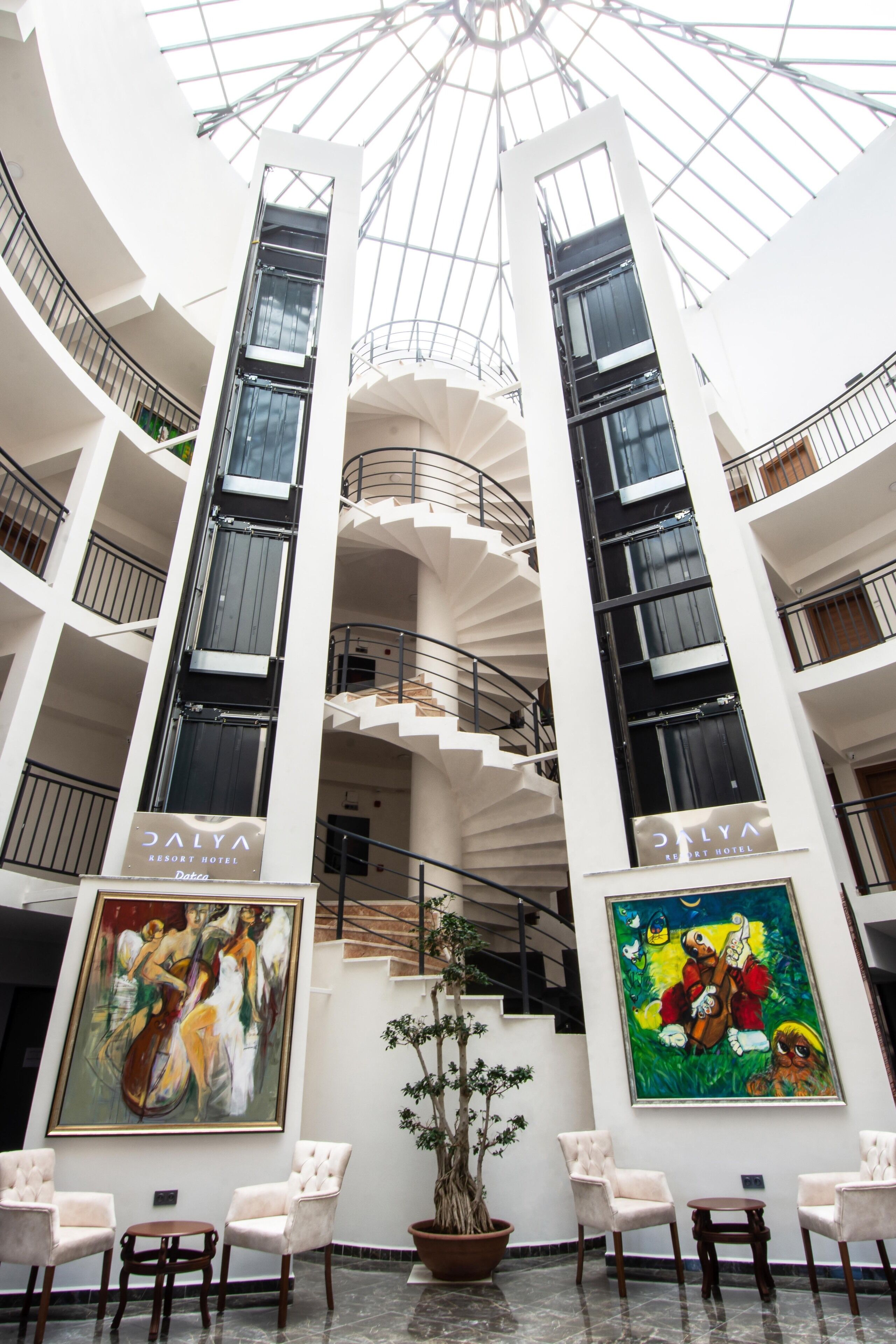 A multi-level atrium with a central staircase, artwork on the walls, and seating areas.