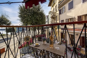 Ein Balkon mit Tisch, einer Weinflasche und einem Teller Essen.