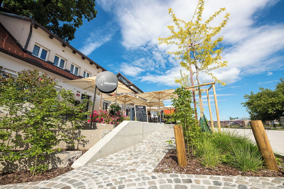 A restaurant patio with outdoor seating, a stone pathway, and a sign for 'Fani & Rozi'.