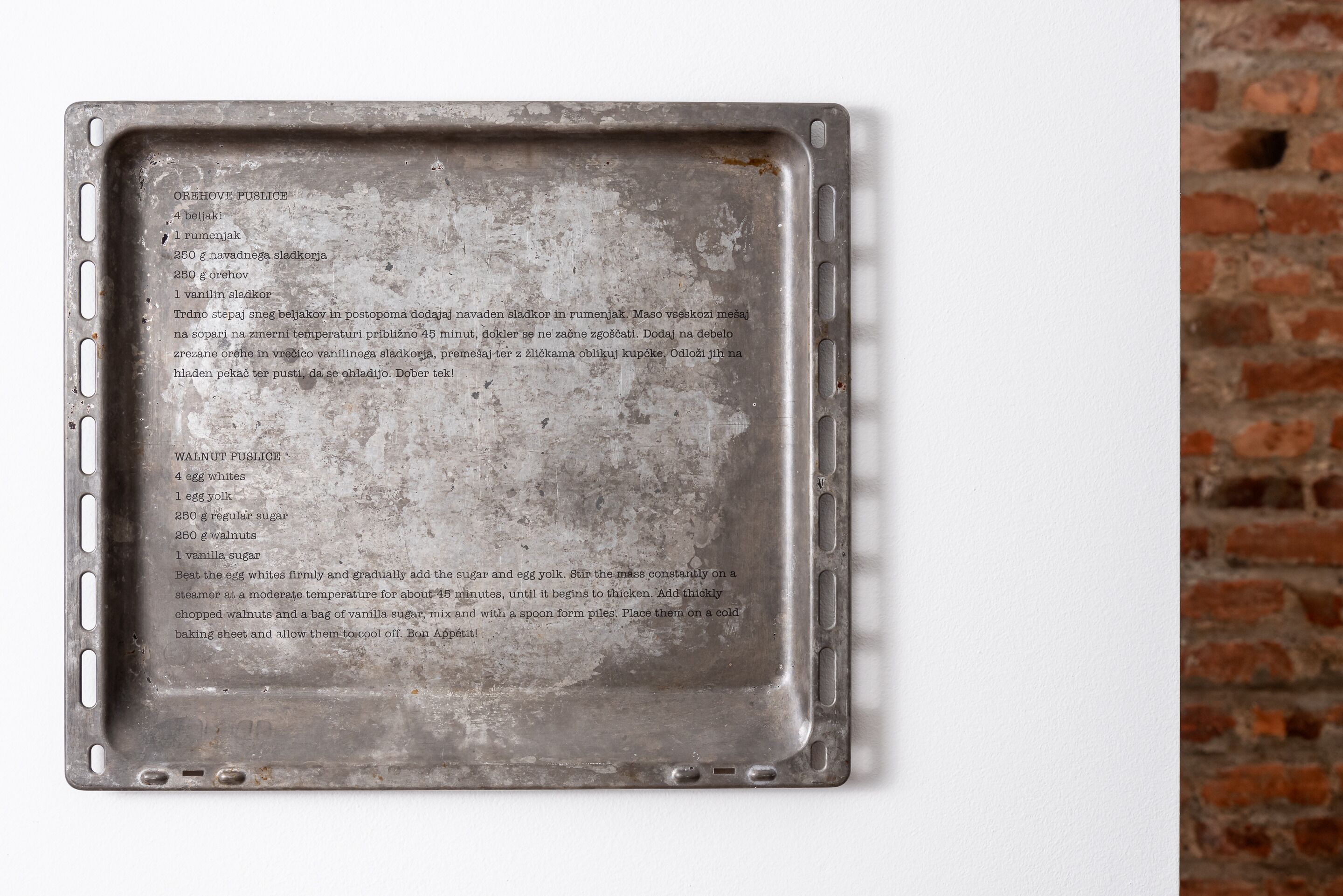 Een metalen bakplaat met instructies voor het maken van een walnoot- en papaverzaadstaart.