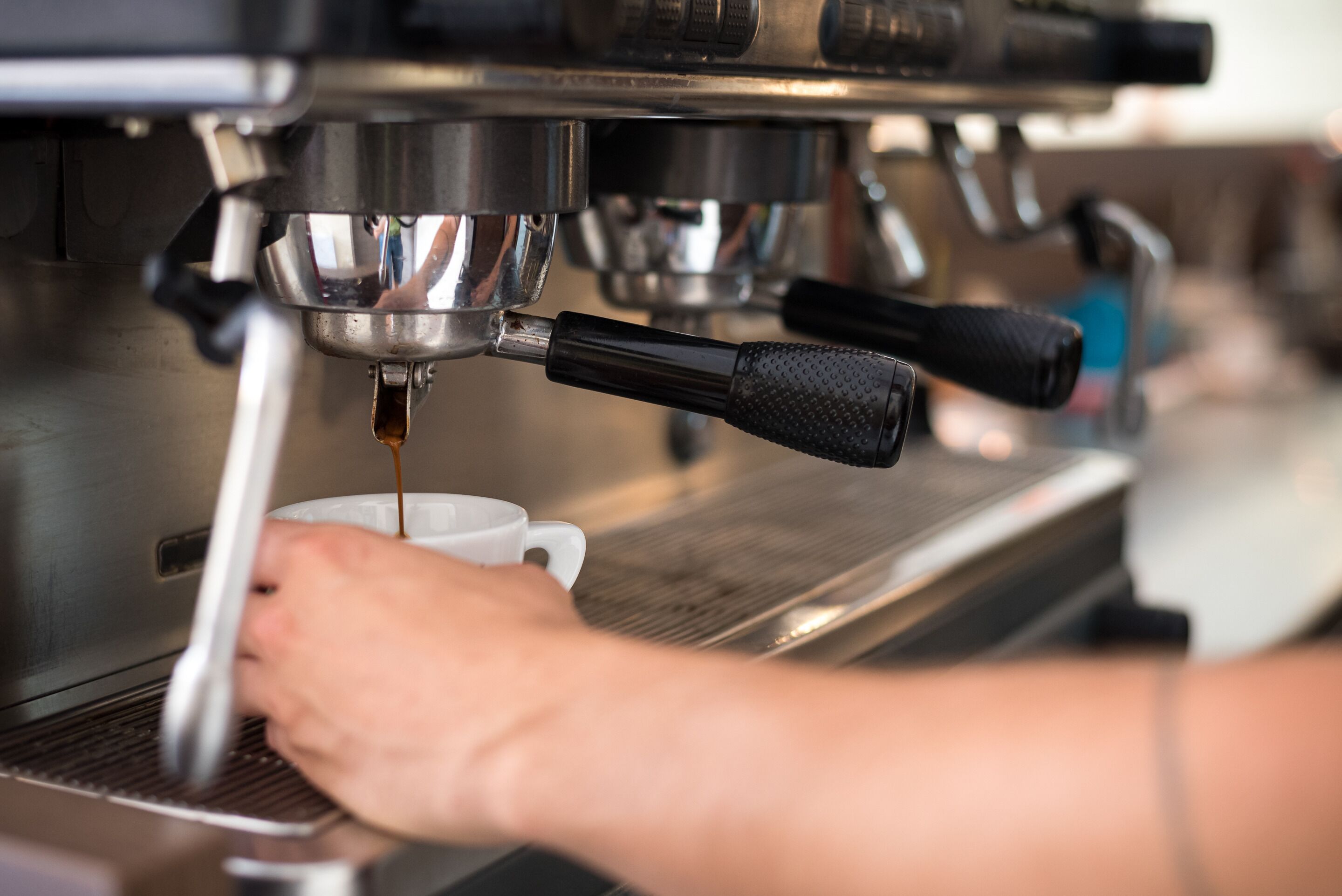 Lähikuva espressokoneesta, joka annostelee espressoa kuppiin.