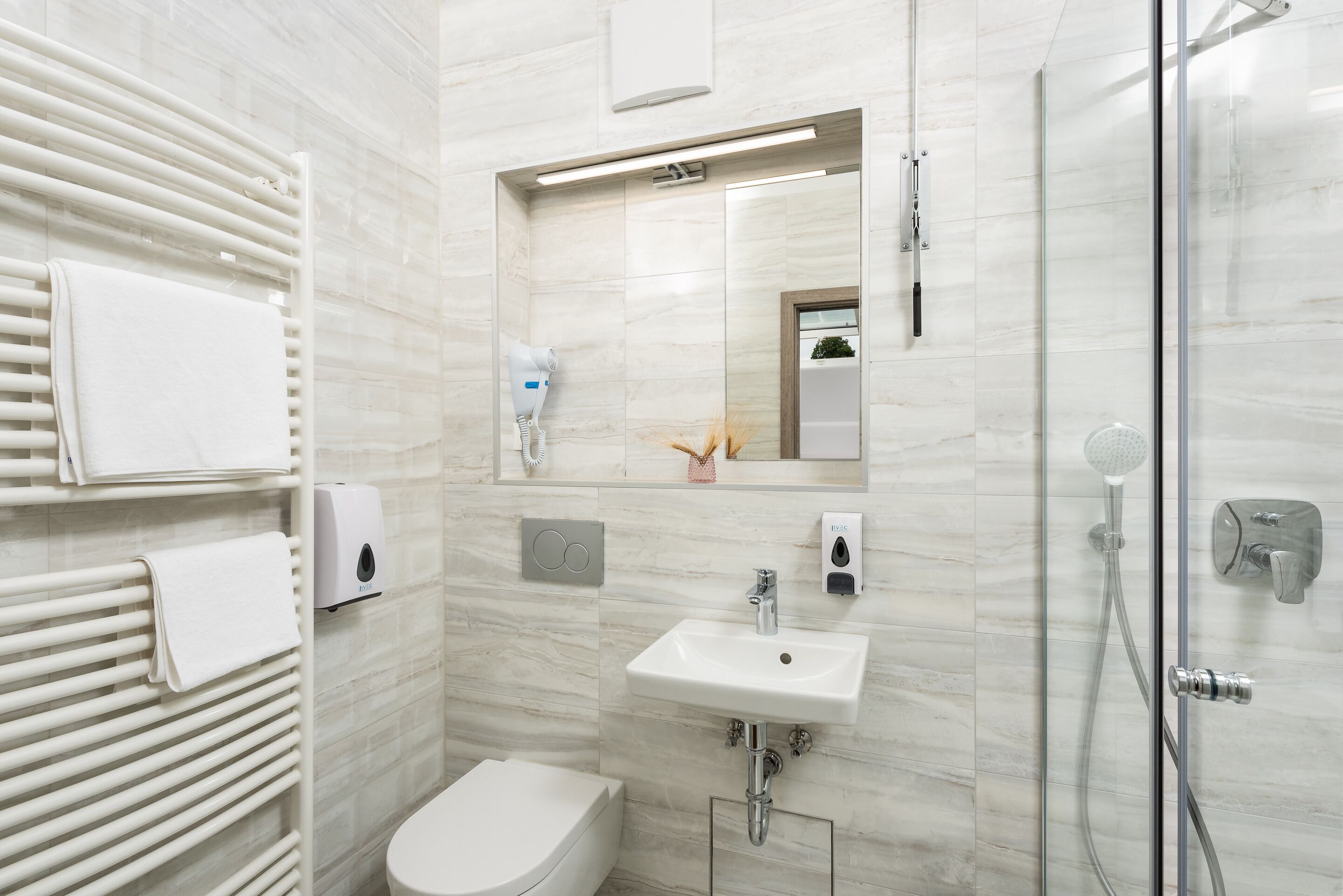Une salle de bain moderne avec une douche à parois de verre, un lavabo blanc et des toilettes.