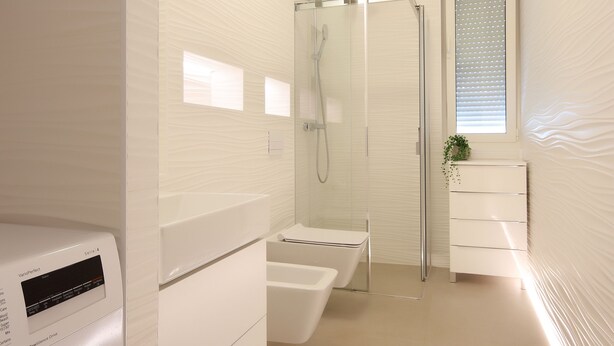 Une salle de bain moderne avec une douche à parois de verre, un lavabo intégré et un lave-linge.