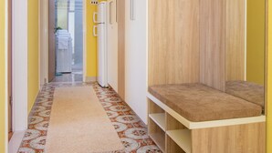 Ein schmaler Flur mit Teppichmuster, einem Holzschrank und einem weißen Kühlschrank.