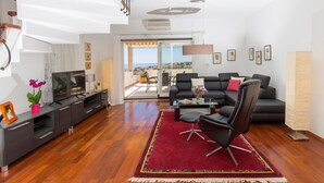 A modern living room with a flat-screen TV, a sofa, a coffee table, and a red rug. - Villa Mia (Dubrovnik)