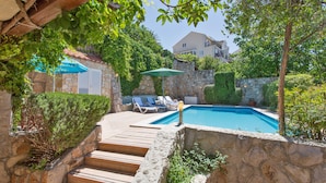 A stone pool with a wooden deck and a stone wall. - Villa Mia (Dubrovnik)