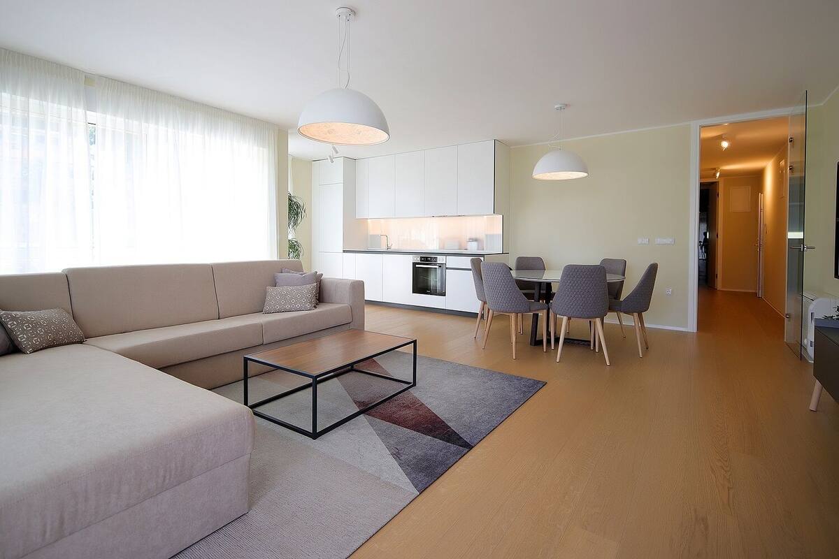 A modern living room with a sofa, coffee table, and dining area with chairs.