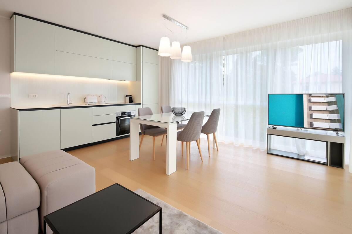 A modern kitchen with a dining area, a TV, and a sofa.