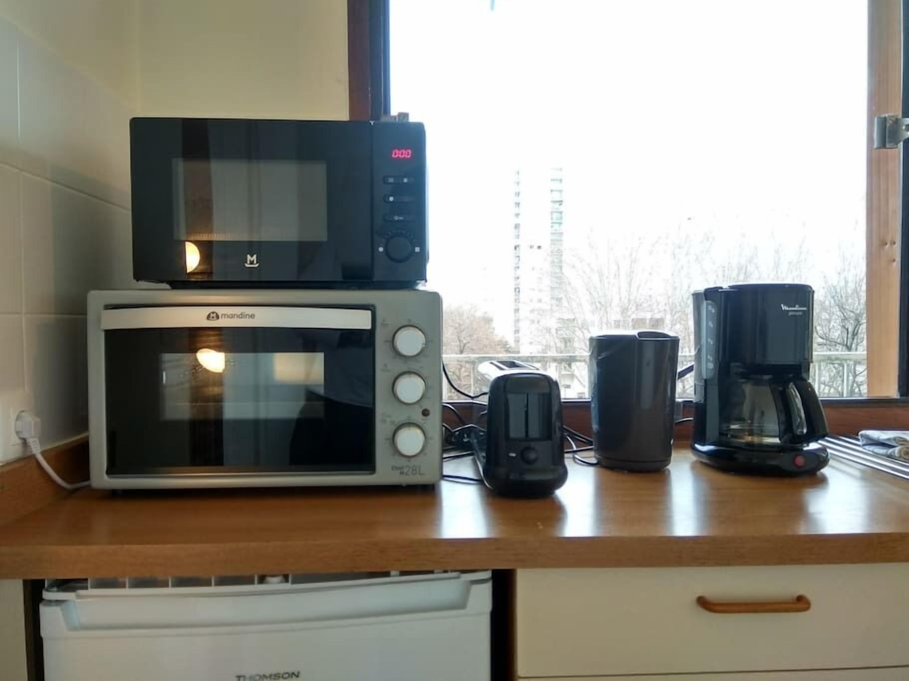 Eine Küche mit Mikrowelle, Toaster und Kaffeemaschine auf einer Holzausziehtafel.