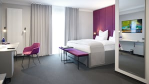 A modern hotel room with a bed, a desk, a chair, and a TV. - Hotel Adler (Münster)
