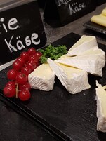 Tabla de quesos con porciones de queso, uvas rojas y perejil.