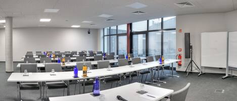 A conference room with long tables, chairs, and a whiteboard.