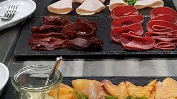 A charcuterie board with various meats, cheeses, and a dipping sauce.