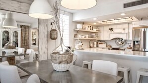 A modern kitchen with white cabinetry, a large island, and pendant lighting.