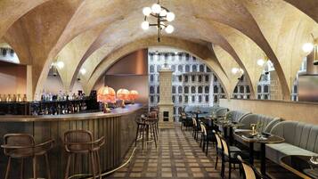 A bar area with a high arched ceiling, a bar counter with stools, and a seating area with tables and chairs.